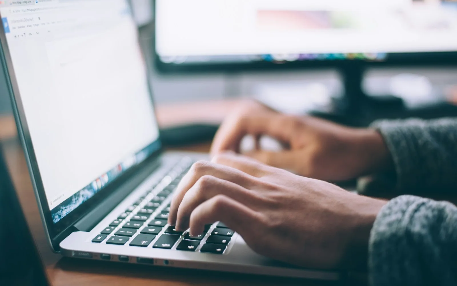 Hands typing on a laptop